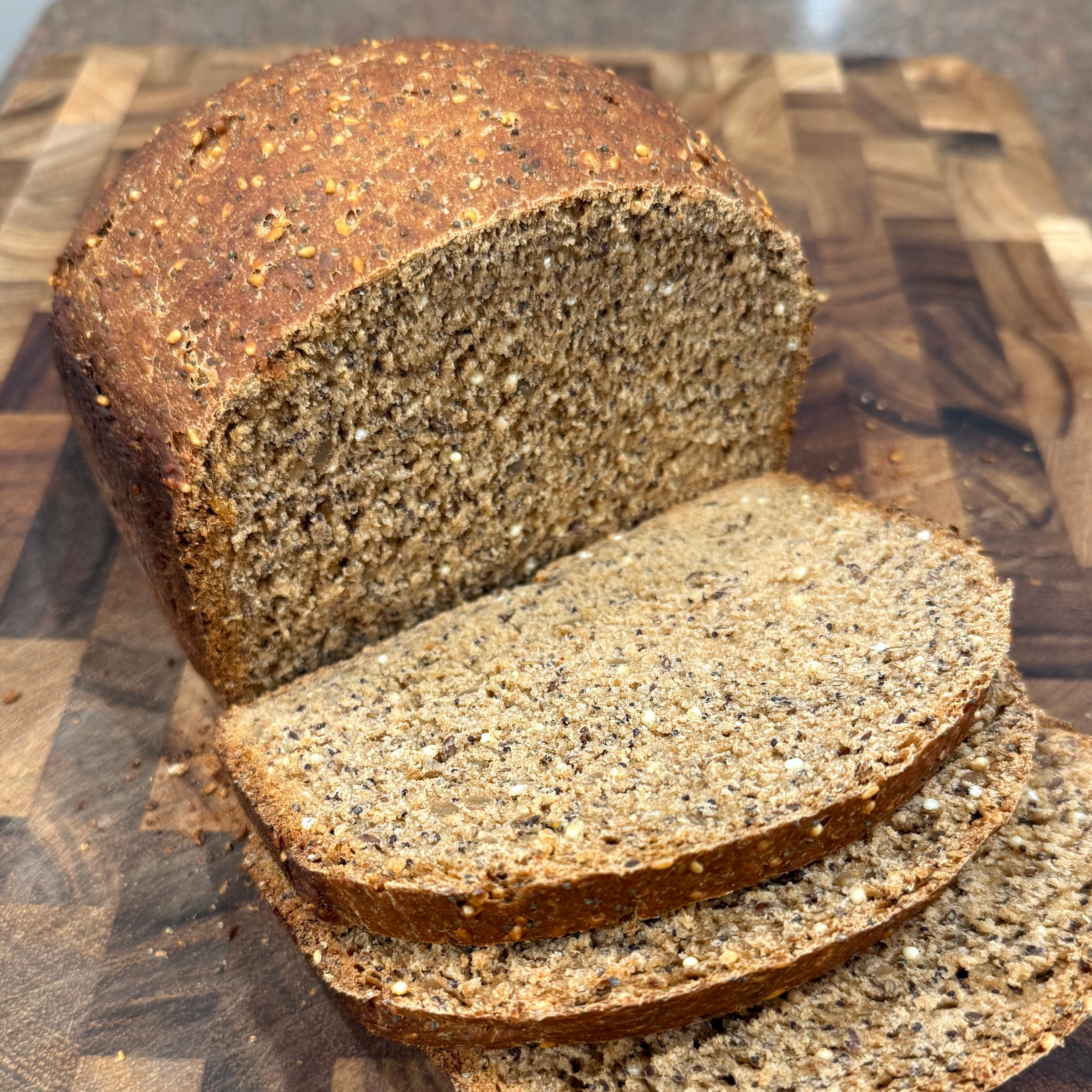 partially sliced seedy wholegrain loaf on butcherblock cutting board