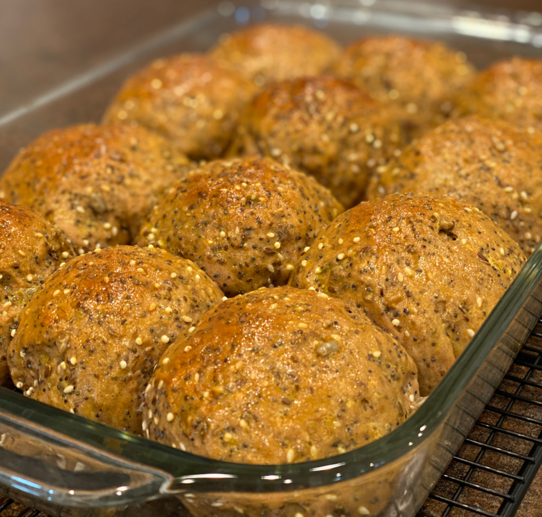 seedy whole grain dinner rolls baked and in a pan