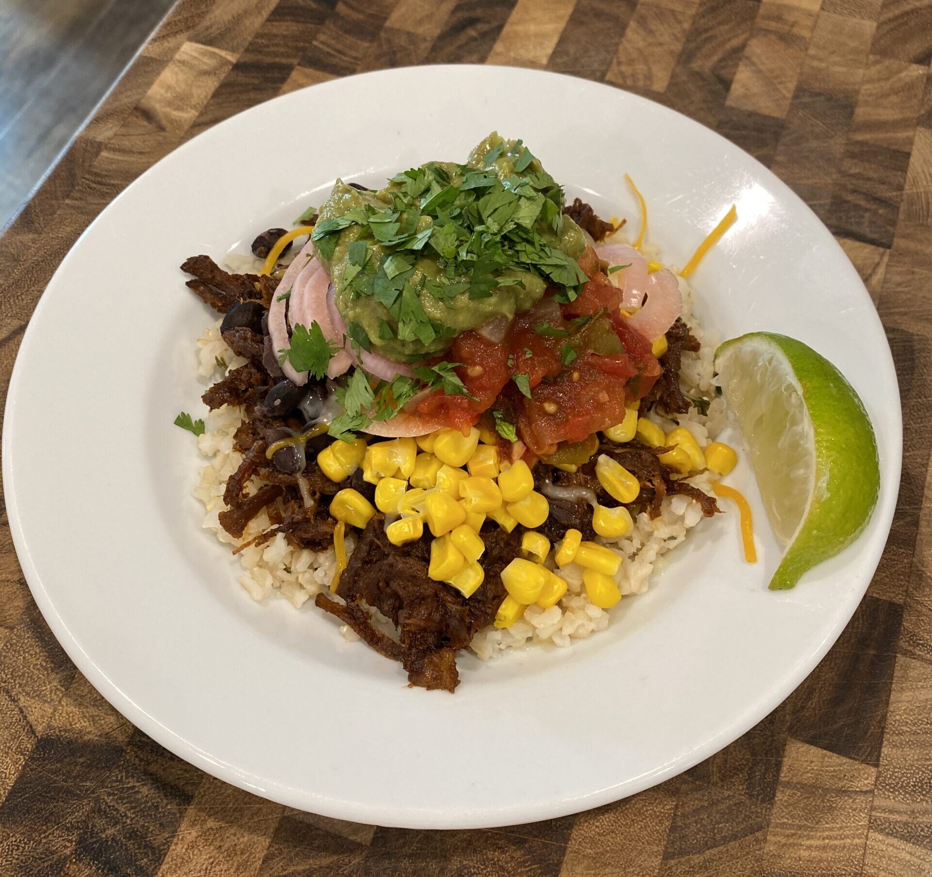 barbacoa beef burrito bowl on a wooden cutting board
